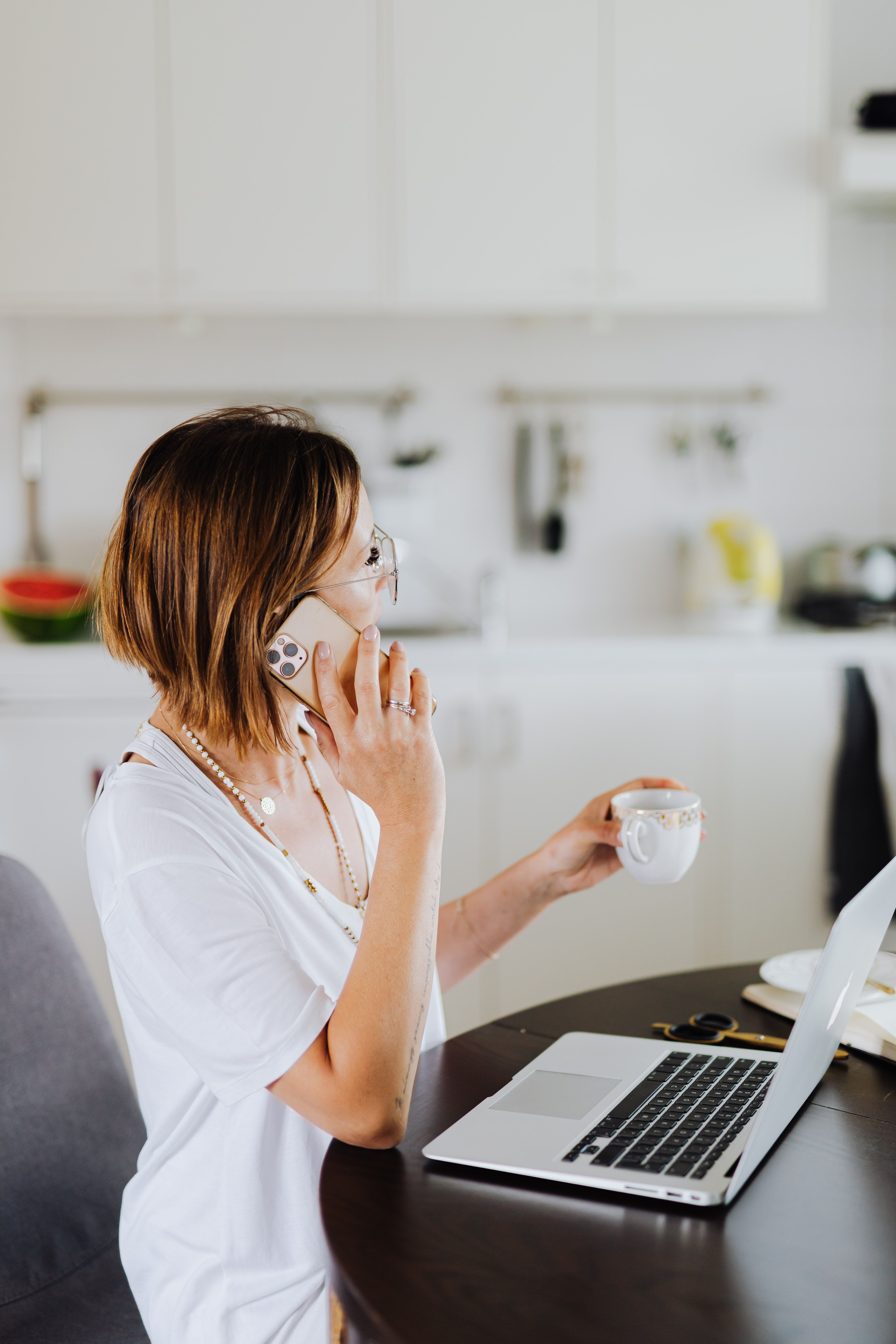 Woman on a phone call with coffee and laptop
